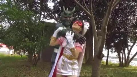 Asian Couple in Costumes Embracing in Park