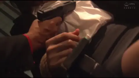 Bound Woman with Guns Held by Man in Suit