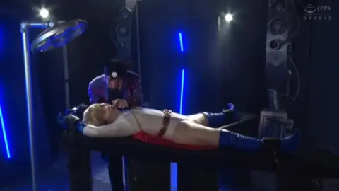 Blonde in White Costume and Red Cape in Dimly Lit Room