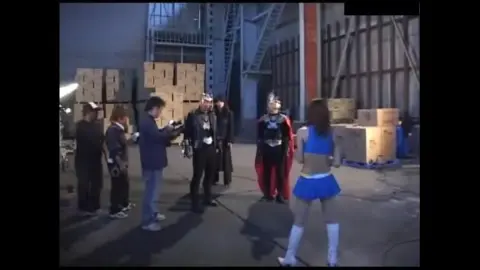 Asian woman in white boots with men in costume