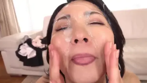 Asian woman applies face mask in living room