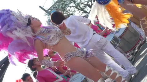 Asian Performers Dancing on Street with Feathered Headdress