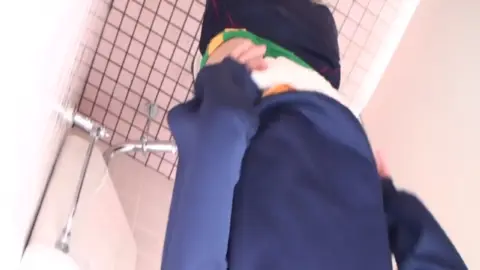 Asian Man Urinating in Pink Tiled Bathroom