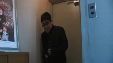 Asian Couple Embraces in Dimly Lit Room