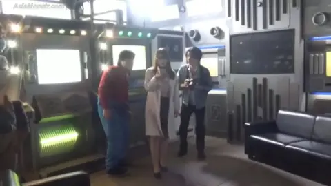 Asian Girl with Glasses in Lab Coat with Muscular Men