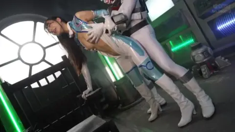 Asian woman in futuristic jumpsuit dominated