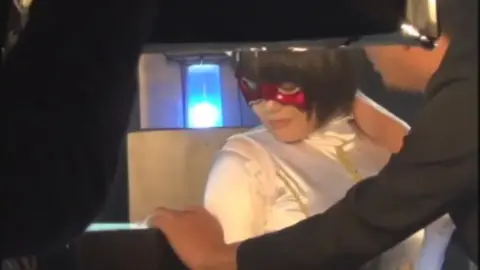 Asian Girl in Costume Restrained by Two Men