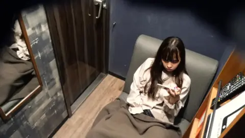 Asian Girl Sitting with Phone in Dimly Lit Room