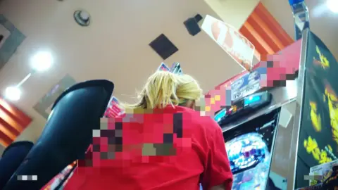 Blonde in Plaid Skirt and Stockings at Arcade