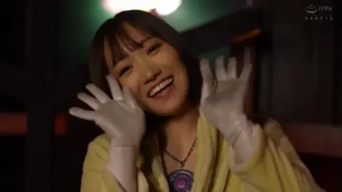 Asian woman in yellow robe and gloves in dimly lit room