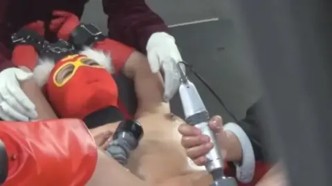 Asian BDSM Scene with Restraints and Costume