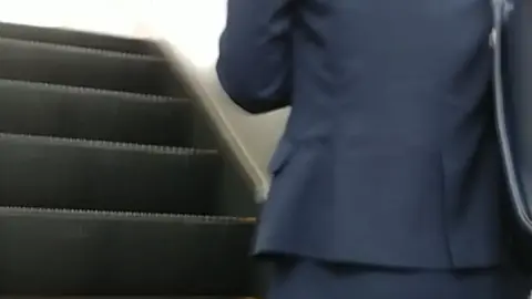 Asian Woman in Business Suit on Escalator