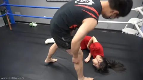 Asian Couple Grappling in Boxing Ring