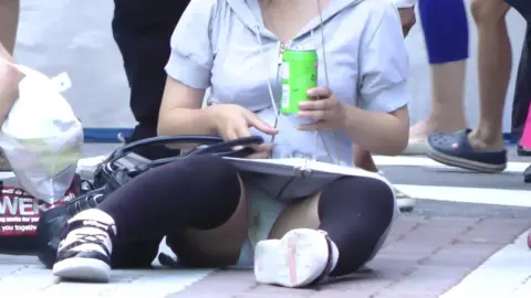 Asian Girl Sitting on Sidewalk