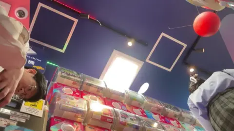 Schoolgirls in Uniform Expose Thighs at Arcade