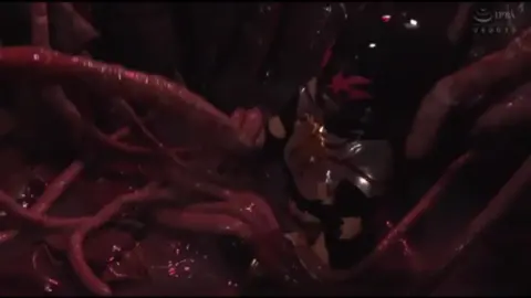 Asian Woman in Black Costume Engulfed by Creature