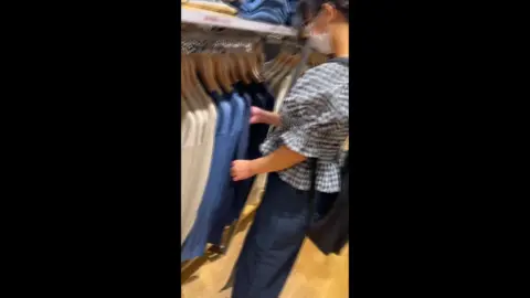 Asian girl tries on clothes in store