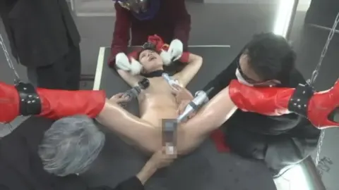 Asian Woman in Restraints and Masks Being Touched