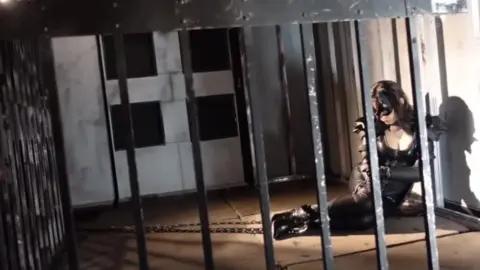 Women in Bodysuits and Masks Pose in Studio and Prison Cell