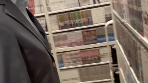 Asian woman in mask and blazer browses books