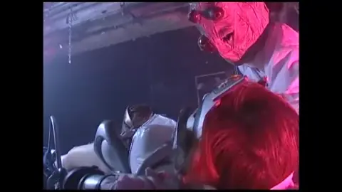 Asian Performers in Silver Costumes Engage in Intimate Acts