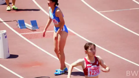 Asian Athletes Stretching on Track
