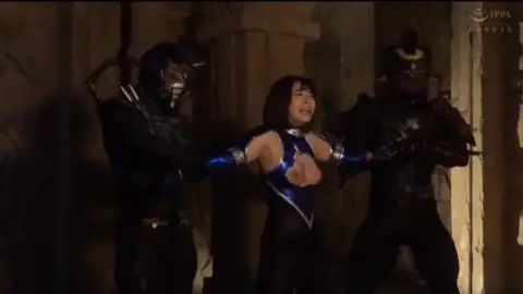 Asian woman restrained by men in dark room