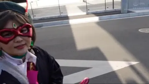 Asian Cosplay Girl with Red Mask and Cape