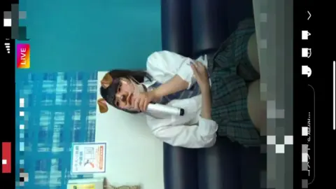 Asian teen in dog ears headband plays with tablet and microphone