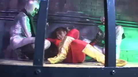 Red and Silver Costumed Performers in Erotic Scene