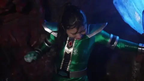 Asian in green costume restrained in dark space